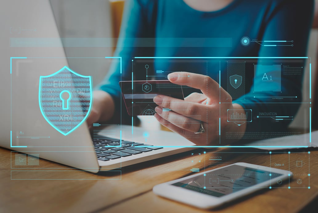 Online shopper using a credit card to make a purchase on his laptop with graphics representing eCommerce security - Shift4Shop
