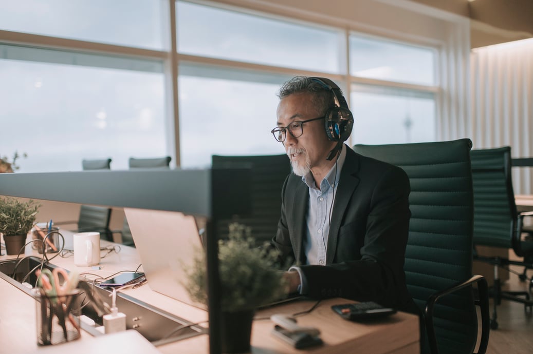 Man talking in a call at his desk on a computer to represent inbound or outbound marketing - Shift4Shop